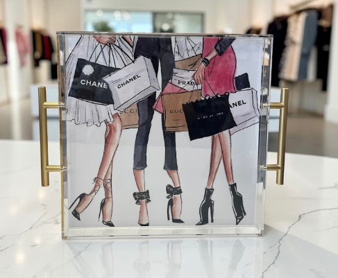 Acrylic tray with gold handles featuring a fashion illustration of women carrying Chanel, Prada, and Gucci shopping bags - designer gift tray from The Pampered Professional, Long Island NYC